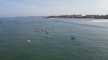Aerial view of people surfing on waves with surfboards when vacation in Bali, Indonesia .