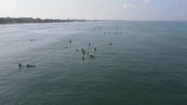 Aerial view of people surfing on waves with surfboards when vacation in Bali, Indonesia .