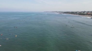 Aerial view of people surfing on waves with surfboards when vacation in Bali, Indonesia .