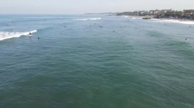 Aerial view of people surfing on waves with surfboards when vacation in Bali, Indonesia .