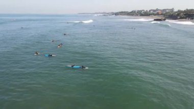 Aerial view of people surfing on waves with surfboards when vacation in Bali, Indonesia .