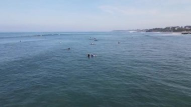 Aerial view of people surfing on waves with surfboards when vacation in Bali, Indonesia .