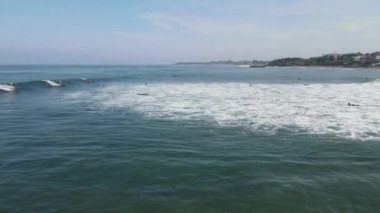 Aerial view of people surfing on waves with surfboards when vacation in Bali, Indonesia .
