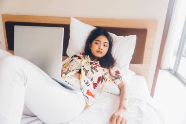 Yataktan çalışırken esneyen uykulu genç bir kadın..