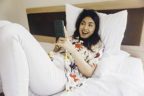 여자가 침대에 핸드폰을 확인하는 — 스톡 사진