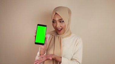 Mutlu ve gülümseyen Asyalı genç kadınlar yeşil boş bir ekran gösteriyorlar..