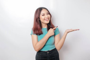 Heyecanlı Asyalı kadın mavi tişört giyip yanındaki fotokopi odasını işaret ediyor, beyaz arka planla izole edilmiş.