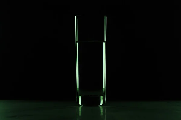 Glas met water in het donker — Stockfoto