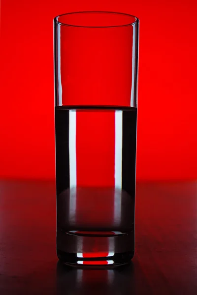 Glass with water with red background — Stock Photo, Image