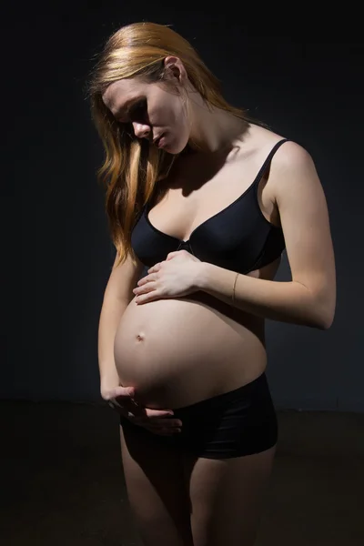 Gravid kvinna med händerna över magen — Stockfoto