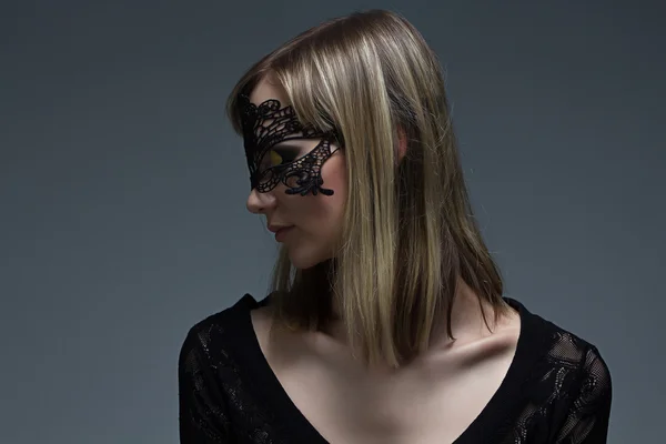 Dziewczyna w czarnej koronki maska patrząc na jej ramieniu — Zdjęcie stockowe