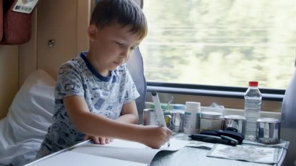 Vidéo d'un garçon de cinq ans dessinant en train en mouvement — Video