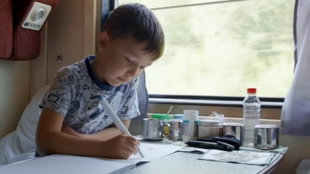Felvétel egy ötéves fiúról, amint rajzol a mozgó vonaton — Stock videók