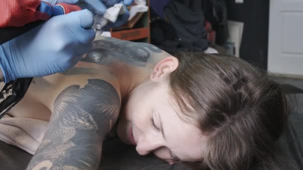 Filmación de una mujer tatuándose de nuevo en el salón — Vídeos de Stock