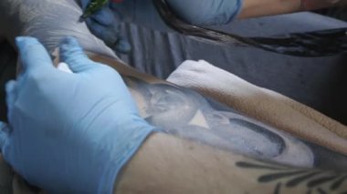 Kadının sırtına dövme yapan adamın yakın çekim videosu.