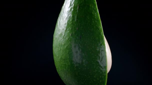 Skjutning av roterande avokado hälften på svart bakgrund — Stockvideo