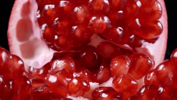 Footage of rotating red pomegranate seeds on black background — Stock Video