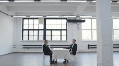 İki adam karşılıklı oturup bekliyor.