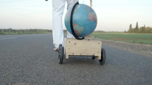 Close-up shooting of man in sunglasses with globe in wooden pushcart — Stock Video