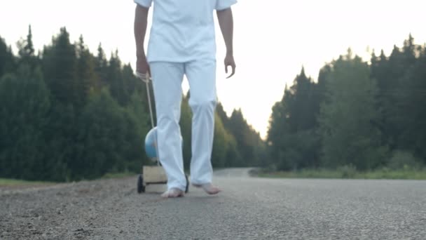 Uomo scalzo in occhiali da sole con globo in pushcart di legno — Video Stock