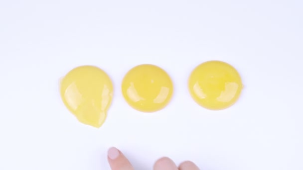 Dedo índice femenino rompiendo yema de huevo amarillo — Vídeos de Stock