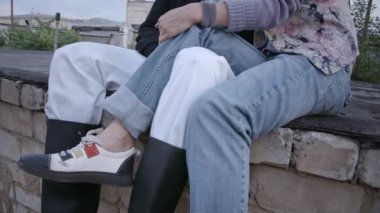Duvarda oturan çiftin videosu, sigara içen adam.