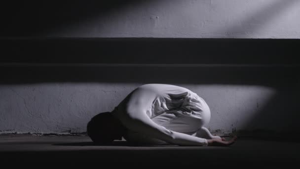 Šílený muž v bílých šatech ležící v pozici plodu a vstávající — Stock video
