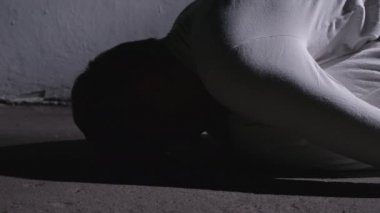 Beyaz elbiseli çılgın adam cenin pozisyonunda yatıyor ve kalkıyor.