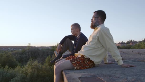 Dos hombres sentados durante el amanecer en verano, sol en sus ojos — Vídeos de Stock
