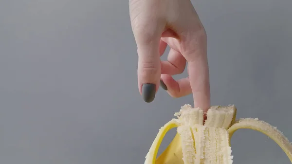 손으로 노란 바나나를 쪼개는 여성의 모습 — 스톡 사진