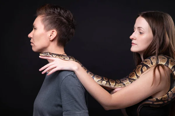 Photo de deux femmes avec python sur les épaules de profil — Photo