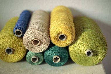 Atölyedeki makarada Retro tarzı iplikçiklerin gölgelerinde yeşil kablo seti. Yaratıcı DIY hobisi için gerekli aletler nakış işlemek gibi işe yarıyor. Renkli ip, yuvarlanan iplik.
