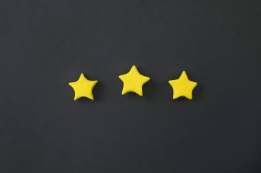Siyah arka planda üç altın yıldız. Altın yıldız şeklinde. Birinci sınıf ürün konsepti, en kaliteli ürün sembolü. Değerlendirme işareti, müşteriden geri bildirim.