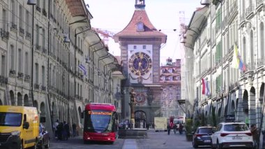 Bern, İsviçre - 03.10. 2022: Şehir trafiği yayalarla ve geçen tramvaylarla dolu. Zahringen Çeşmesi ya da Zahringerbrunnen ayı heykeli. Zytglogge Saat Kulesi, Kramgasse Caddesi.