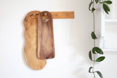 Tahta kesme tahtaları duvarda asılı. Sade, sade, modern mutfak iç mimarisi, yeşil bitki ve beyaz raf. Geleneksel mutfakta dekorasyon.