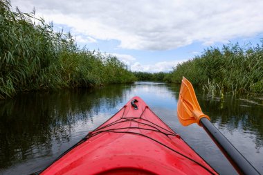 Kayaker point of view. Kayak bow with a view on the river and rushes.   River kayaking concept. Active vacations in wild nature.