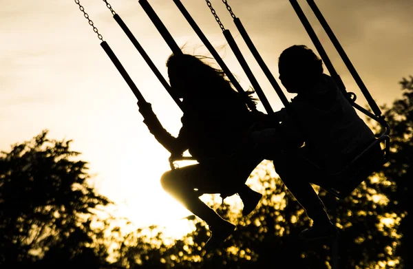 Unga flickor på merry go round vid solnedgången — Stockfoto