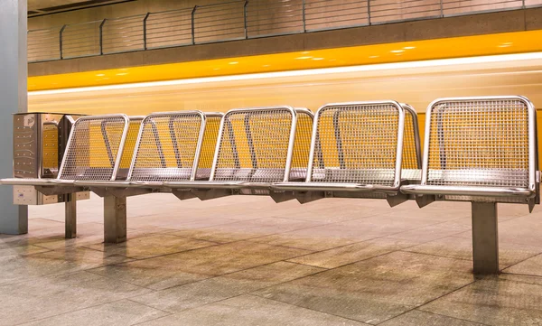 Sarı tren metal koltukların arkasında hızlandırmak — Stok fotoğraf