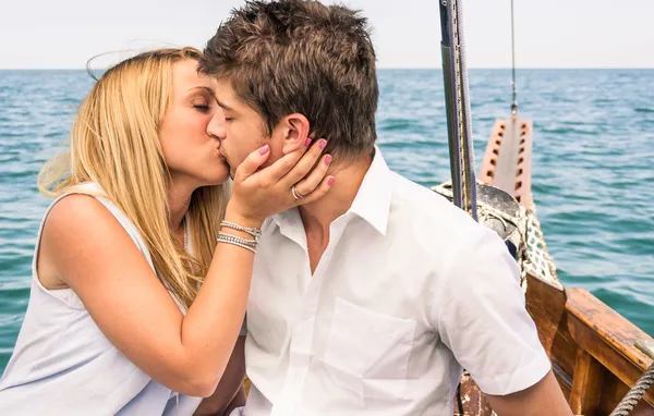 Casal apaixonado beijando em um barco à vela no meio do mar — Fotografia de Stock