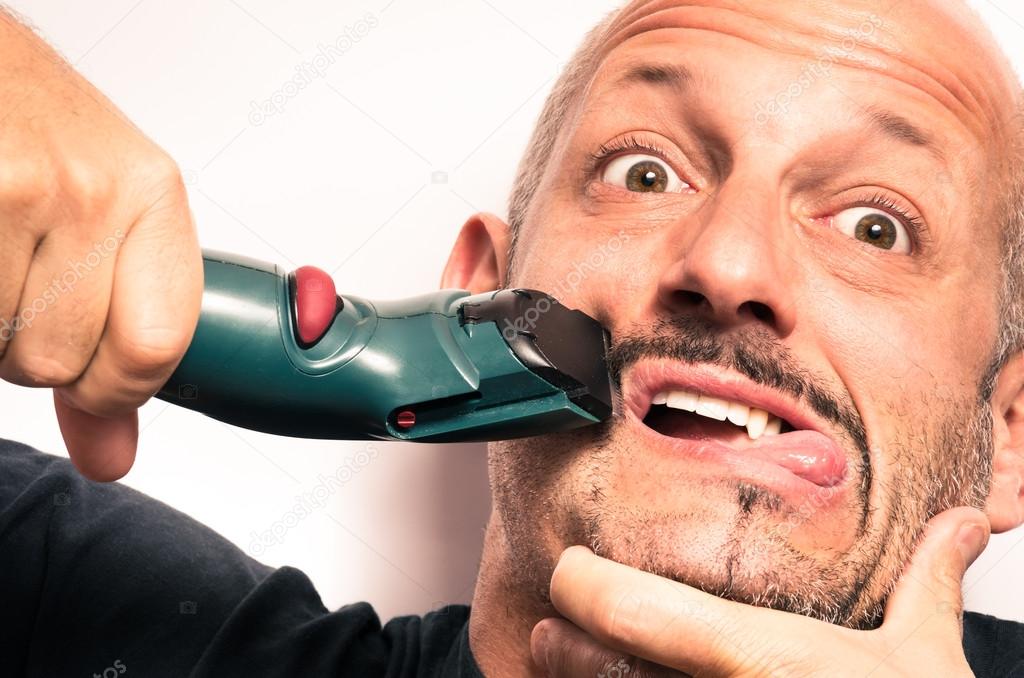 Young man having Troubles with electric Shaver