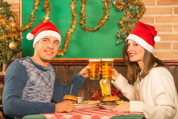 Pasangan bahagia di restoran dengan topi Santa — Stok Foto