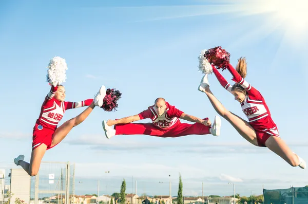 Cheerleaders squadra che esegue un salto con allenatore maschile — Foto Stock