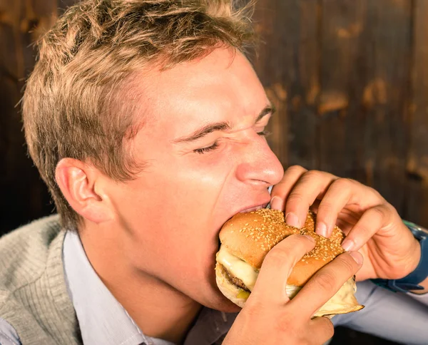 Bonito homem comendo Cheeseburger — Fotografia de Stock