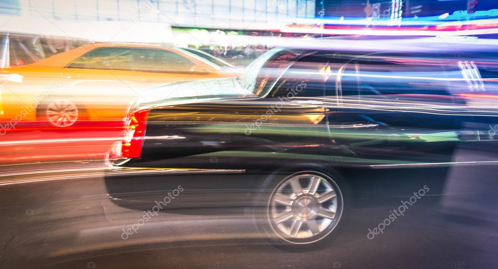 Speeding car and taxi cab in the night traffic of New York City