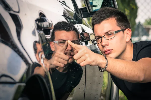 Jovem com óculos inspecionando um carro de luxo antes de um comércio em segunda mão — Fotografia de Stock