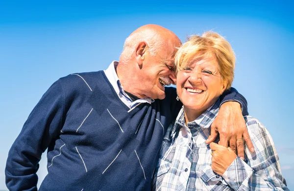 Casal sênior feliz apaixonado durante a aposentadoria - Estilo de vida idoso alegre com o homem sussurrando e sorrindo com sua esposa — Fotografia de Stock