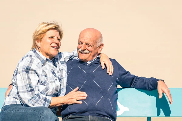 Glückliche verliebte Senioren amüsieren sich am Strand - fröhlicher Lebensstil im Alter mit Mann und Frau, die draußen auf einer Bank lachen — Stockfoto