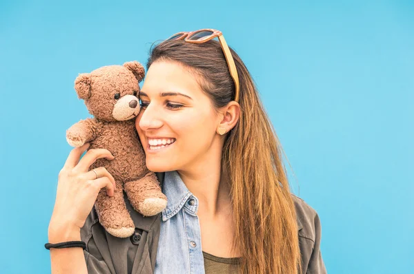 Jonge vrouw met kleine vintage teddybeer op haar schouder op een blauwe muur achtergrond — Stockfoto