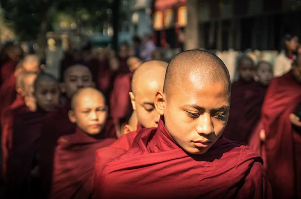 AMARAPURA, MYANMAR - FEBRUARY 10, 2014: young buddhist novices walk to collect alms and offerings in the monastery of Maha Gandhayon Kyaung near Mandalay in Myanmar. — Stock Photo, Image