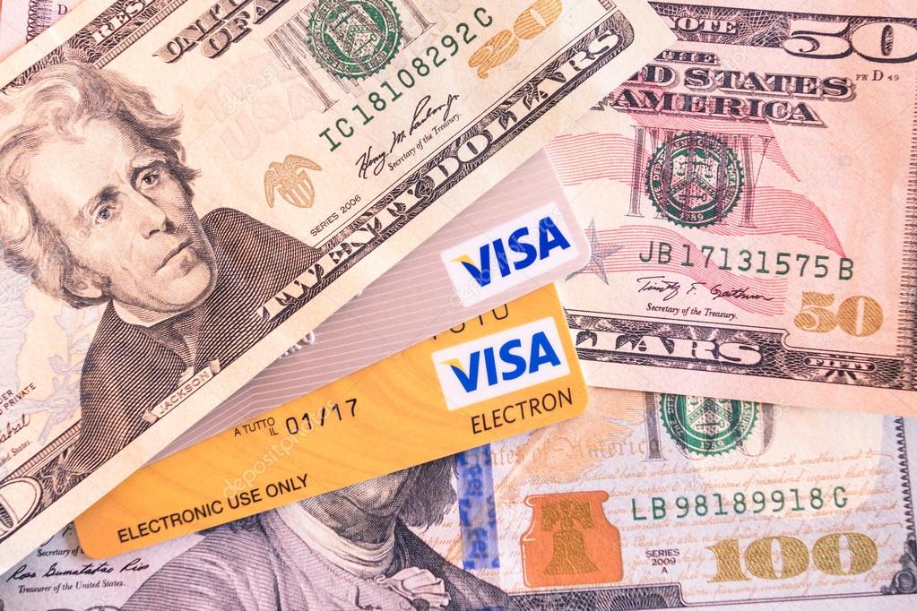 BANGKOK, THAILAND - FEBRUARY 21, 2014: Visa and Visa Electron credit cards and dollar bills. Visa Inc. is an american financial services corporation based in Foster City, California, United States.